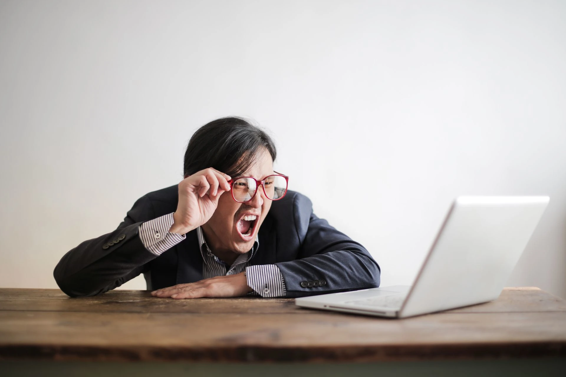 A man screaming comically at his laptop.