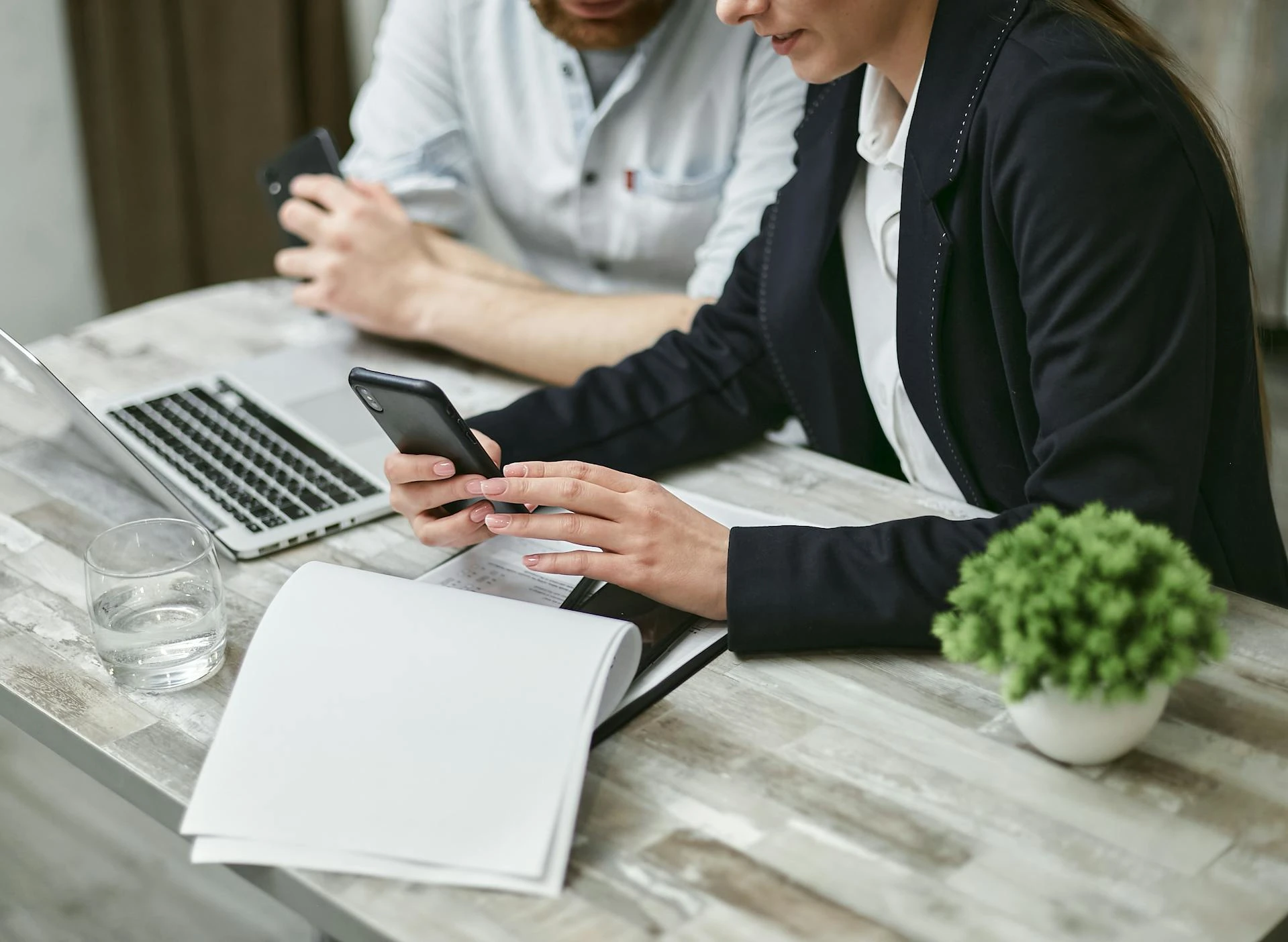 Two people in an office setting using xosend to transfer a file from a smartphone to a laptop.